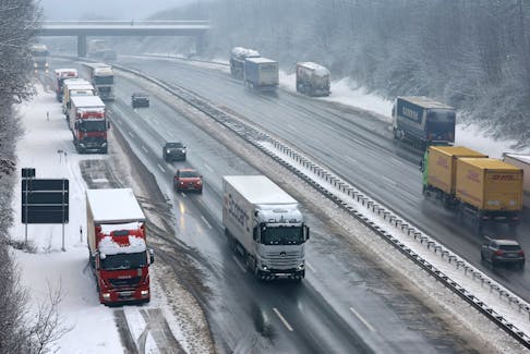 Vehicles pass trucks, parked at the emergency lane after heavy snowfall at the A3 highway, near Aegidinberg, Germany, January 18, 2024.    