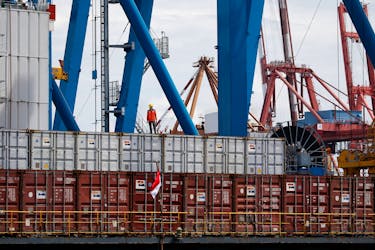 A worker stands on a container at Tanjung Priok Port in Jakarta, Indonesia, January 11, 2021. Picture taken January 11, 2021.