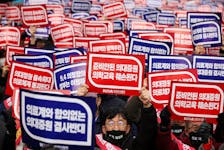 Doctors chant slogans during a rally to protest against government plans to increase medical school admissions in Seoul, South Korea, March 3, 2024. The banners read "Oppose increasing medical school admissions without talks with the medical community" (in blue) and "Medical education will be harmed in increasing medical school admissions" (in red). 