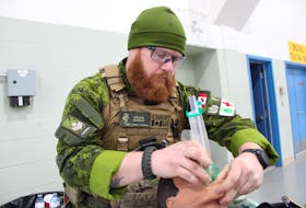 Aidan Angus, a flight medical technician with the Canadian Army Reserves, demonstrates on a dummy how to open up one's throat for breathing in an emergency situation. Although he joined the forces with no more than a first aid certification, he now has the qualifications to address a variety of medical situations.