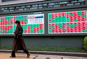 A man walks past an electronic board showing Japan's Nikkei average and stock prices outside a brokerage, in Tokyo, Japan, March 17, 2023.