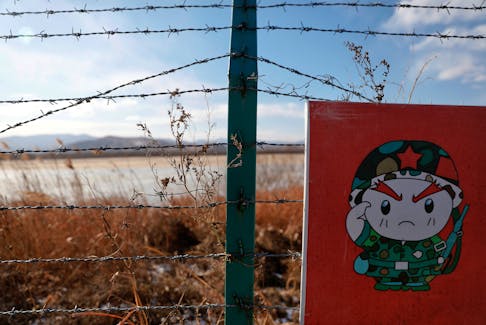 A cartoon soldier is depicted on part of a warning sign on barbed wire on the Chinese side of the border between Russia, China and North Korea near the town of Hunchun, China, November 24, 2017.