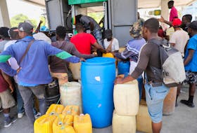People gather to buy gasoline at a petrol station as violence spreads and armed gangs expand their control over the capital, in Port-au-Prince, Haiti March 29, 2024.