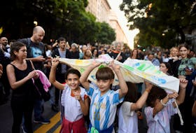 Children hold a banner as Argentine university students, unions, and social groups march to protest against President Javier Milei's "chainsaw" cuts on public education, in Buenos Aires, Argentina, April 23, 2024.