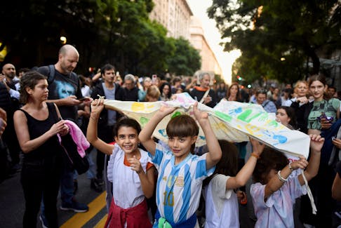 Children hold a banner as Argentine university students, unions, and social groups march to protest against President Javier Milei's "chainsaw" cuts on public education, in Buenos Aires, Argentina, April 23, 2024.