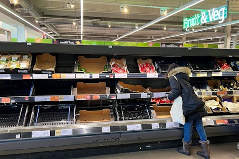 A shopper looks amongst a partially empty fruit and vegetable display in an aisle at a Sainsbury's supermarket, as Britain experiences a seasonal shortage of some fruit and vegetables, in London, Britain, February 26, 2023.