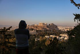 A man looks at the Acropolis and the cityscape in Athens, Greece, April 12, 2024.
