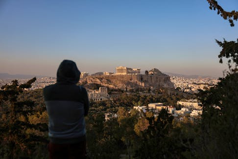 A man looks at the Acropolis and the cityscape in Athens, Greece, April 12, 2024.