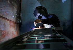 A worker welds steel pipes to make a counter at a steel furniture manufacturing unit in Ahmedabad, India September 1, 2016.