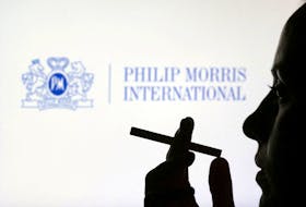 A woman poses with a cigarette in front of Philip Morris International logo in this illustration taken July 26, 2022.