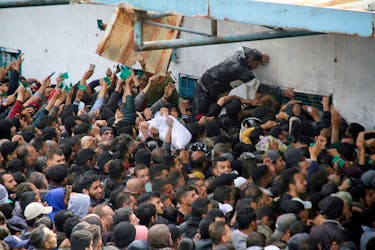 Palestinians gather to receive aid outside an UNRWA warehouse as Gaza residents face crisis levels of hunger, amid the ongoing conflict between Israel and Hamas, in Gaza City March 18, 2024.