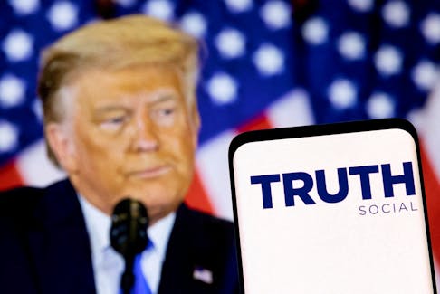 The Truth social network logo is seen on a smartphone in front of a display of former U.S. President Donald Trump in this picture illustration taken February 21, 2022.