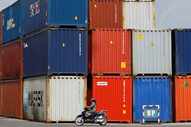 A woman rides a motorcycle as she passes containers at Hai Phong port, Vietnam September 25, 2018. Picture taken September 25, 2018.