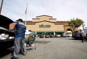 An Amazon shopper and courier loads groceries into his trunk outside a Whole Foods Market grocery store in Pasadena, California, U.S., March 31, 2020.