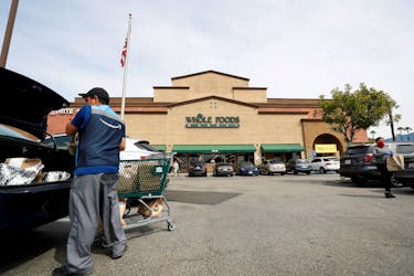 An Amazon shopper and courier loads groceries into his trunk outside a Whole Foods Market grocery store in Pasadena, California, U.S., March 31, 2020.