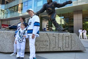 Katherine, Lawrence and Michal Grajewski (from left) pose for a photo by the Dale Hawerchuk statue outside the Party at the Plaza in True North Square as the Winnipeg Jets opened their playoff series against the Colorado Avalanche on Sunday. 
