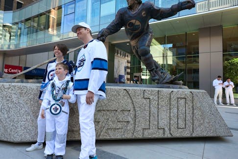 Katherine, Lawrence and Michal Grajewski (from left) pose for a photo by the Dale Hawerchuk statue outside the Party at the Plaza in True North Square as the Winnipeg Jets opened their playoff series against the Colorado Avalanche on Sunday. 
