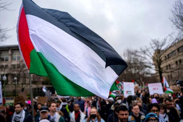 A Palestinian flag flies over a group of pro-Palestinian demonstrators as they march outside the Israeli embassy to call for a ceasefire in Gaza, amid the ongoing conflict between Israel and the Palestinian Islamist group Hamas, during a protest in Washington, U.S., March 2, 2024.