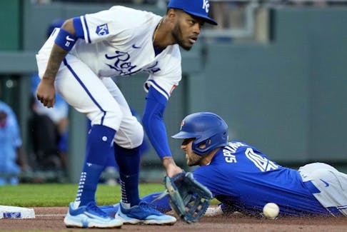 George Springer of the Toronto Blue Jays beats the tag by Kansas City Royals third baseman Maikel Garcia to advance to third on a single by Bo Bichette during the third inning of a baseball game April 23, 2024, in Kansas City, Mo.