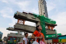 People walk past a Skytrain (Bangkok Mass Transit System) construction site in Bangkok, Thailand May 13, 2018.