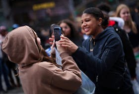 A young woman makes a video of her friends with a mobile phone to post on TikTok in Times Square in New York City, New York, U.S., March 13, 2024.