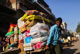 A labourer reacts as he transports a cart full of sacks at a wholesale market in the old quarters of Delhi, India, June 7, 2023.