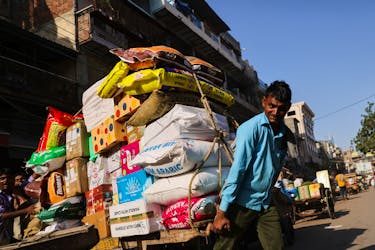 A labourer reacts as he transports a cart full of sacks at a wholesale market in the old quarters of Delhi, India, June 7, 2023.