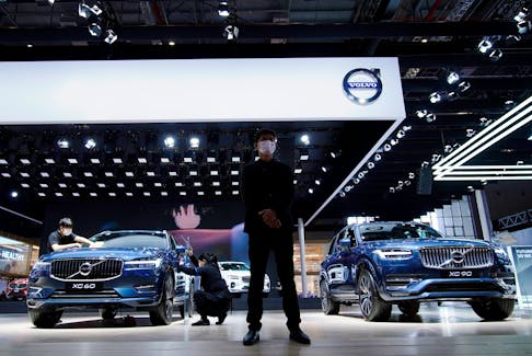 A staff member stands in front of Volvo XC60 and XC90 SUVs displayed at its booth during a media day for the Auto Shanghai show in Shanghai, China April 20, 2021.