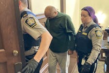 Satrajpal Singh Rai hides the lower part of his face with his shirt as he is escorted into Halifax provincial court Thursday to face three charges, including attempted murder, from an April 3 machete attack on his mother. Rai's case will return to court next week, after he meets with lawyer Anna Mancini.