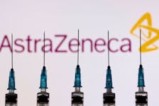 Syringes with needles are seen in front of a displayed AstraZeneca logo in this illustration taken, November 27, 2021.