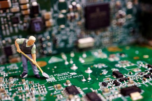 A worker miniature is placed among printed circuit boards with semiconductor chips, in this illustration picture taken July 5, 2023.