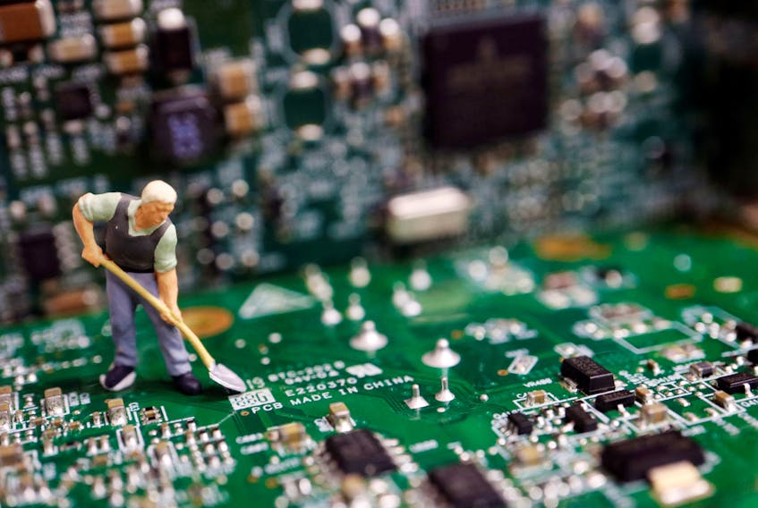 A worker miniature is placed among printed circuit boards with semiconductor chips, in this illustration picture taken July 5, 2023.