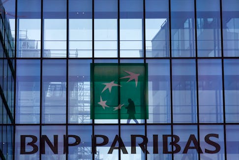 A man is silhouetted as he walks behind the logo of BNP Paribas at the bank's building in Issy-les-Moulineaux, near Paris, France, February 3, 2022.