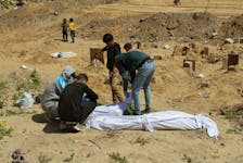 Palestinians cover a body, which was buried in a mass grave, amid the ongoing conflict between Israel and Hamas, in northern Gaza Strip, April 15, 2024.