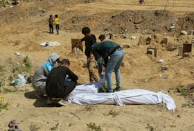 Palestinians cover a body, which was buried in a mass grave, amid the ongoing conflict between Israel and Hamas, in northern Gaza Strip, April 15, 2024.