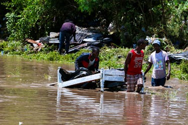 Residents carry a bed they salvaged from flood waters after Athi River burst its banks and marooned their homes following heavy rainfall in Kwa Mang'eli settlement of Machakos county near Nairobi, Kenya April 24, 2024.