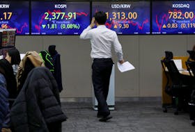 A currency dealer walks past electronic boards showing the Korean Composite Stock Price Index  (KOSPI) and the exchange rate between the U.S. dollar and South Korean won at a dealing room of a bank, in Seoul, South Korea, March 16, 2023.
