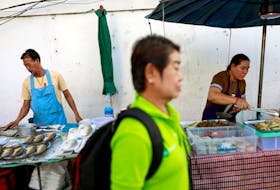 A person walks pass some vendors on the street at a market in Bangkok, Thailand, September 26, 2019.