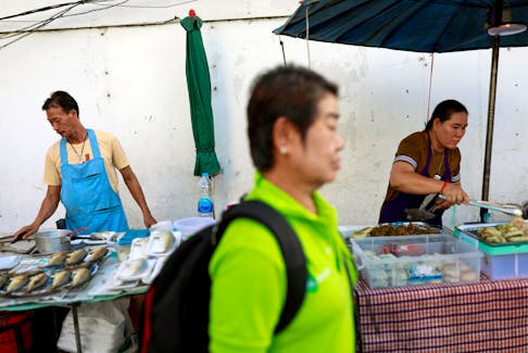 A person walks pass some vendors on the street at a market in Bangkok, Thailand, September 26, 2019.