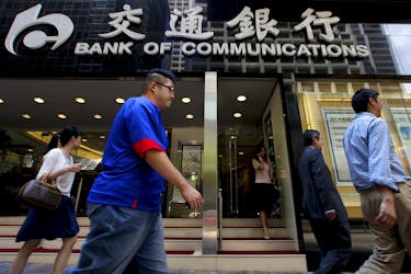 People walk past the Bank of Communications at its central branch in the financial district of Hong Kong August 19, 2009.