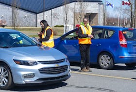 Julie Porter, left, and Lacy Christmas collect donations from passing traffic at an impromptu "toll booth" on Towerview Drive in Membertou on Friday. The pair were helping local elders raise funds for an annual pilgrimage to Sainte Anne de Beaupre Basilica in Quebec. Saint Anne is revered among Mi'kmaw Catholics. Mitchell Ferguson/Cape Breton Post