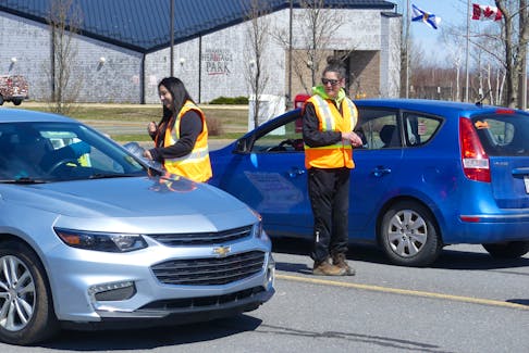 Julie Porter, left, and Lacy Christmas collect donations from passing traffic at an impromptu "toll booth" on Towerview Drive in Membertou on Friday. The pair were helping local elders raise funds for an annual pilgrimage to Sainte Anne de Beaupre Basilica in Quebec. Saint Anne is revered among Mi'kmaw Catholics. Mitchell Ferguson/Cape Breton Post