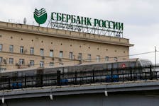 A metro train moves on a bridge, with the logo of Sberbank on top of a building seen in the background, in central Moscow, Russia, April 22, 2016.