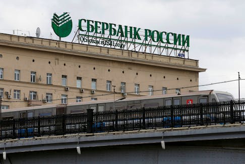 A metro train moves on a bridge, with the logo of Sberbank on top of a building seen in the background, in central Moscow, Russia, April 22, 2016.