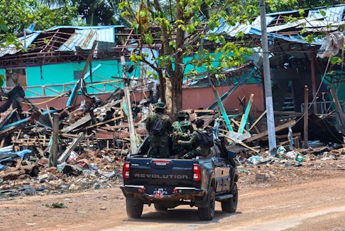 Soldiers from the Karen National Liberation Army (KNLA) patrol on a vehicle, next to an area destroyed by Myanmar's airstrike in Myawaddy, the Thailand-Myanmar border town under the control of a coalition of rebel forces led by the Karen National Union, in Myanmar, April 15, 2024.