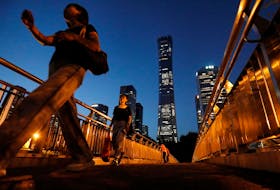 Pedestrians walk on an overpass near skyscrapers at the  Central Business District (CBD) in Beijing, China August 21, 2023.