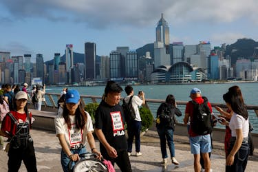 Mainland Chinese tourists walk in front of the skyline of buildings at Tsim Sha Tsui, in Hong Kong, China May 2, 2023.