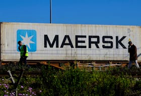 Workers talk on their mobile phones, as a Maersk container is transported by a train, near a port of Barcelona, Spain April 26, 2024.