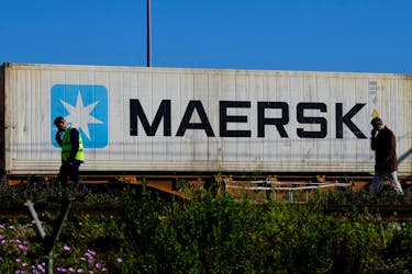 Workers talk on their mobile phones, as a Maersk container is transported by a train, near a port of Barcelona, Spain April 26, 2024.