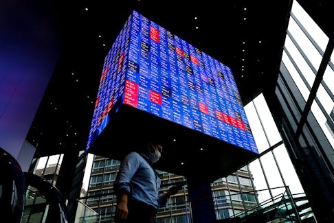 A man walks under an electronic screen showing Japan's Nikkei share price index inside a conference hall in Tokyo, Japan June 14, 2022.